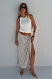 White Ribbed Tank worn with a silver sequin wrap skirt and sunglasses, leaning against a white wall.