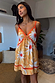 Yellow Sun Mini Dress featuring an orange sun print, crochet trims and tie-front detail, ideal for a vacation.