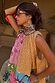 Yellow Tort Wiggle Arm Sunglasses with light blue lenses, styled with a colourful patterned top and neck scarf.
