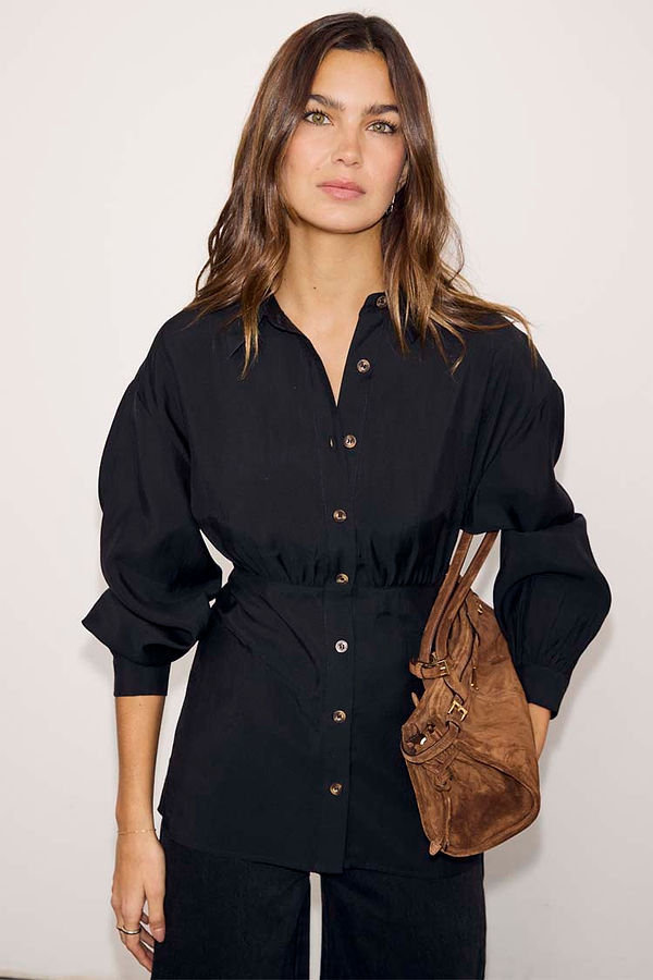 Black Zoe Shirt featuring a cinched waist seam, button-down front and puffed sleeves, styled with a brown bag.
