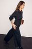 Longline Black Zoe Shirt featuring a waist seam and button fastening, paired with wide-leg trousers.