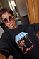 Black Fruit Shop Sweatshirt featuring a blue striped awning and hanging fruit print, worn by a model.