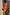 Thumbnail for Multicoloured Abstract Beaded Fringe Bag with pink tassels, held by a model wearing a matching print maxi dress.