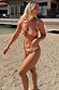 Abstract Ruched Bikini Top with painterly sunset tones and gathered cups, worn on a sandy beach.