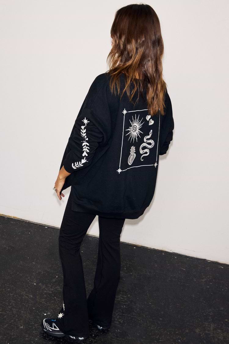 Black oversized sweatshirt with ecru sun and snake embroidery on the back and floral sleeve detailing.