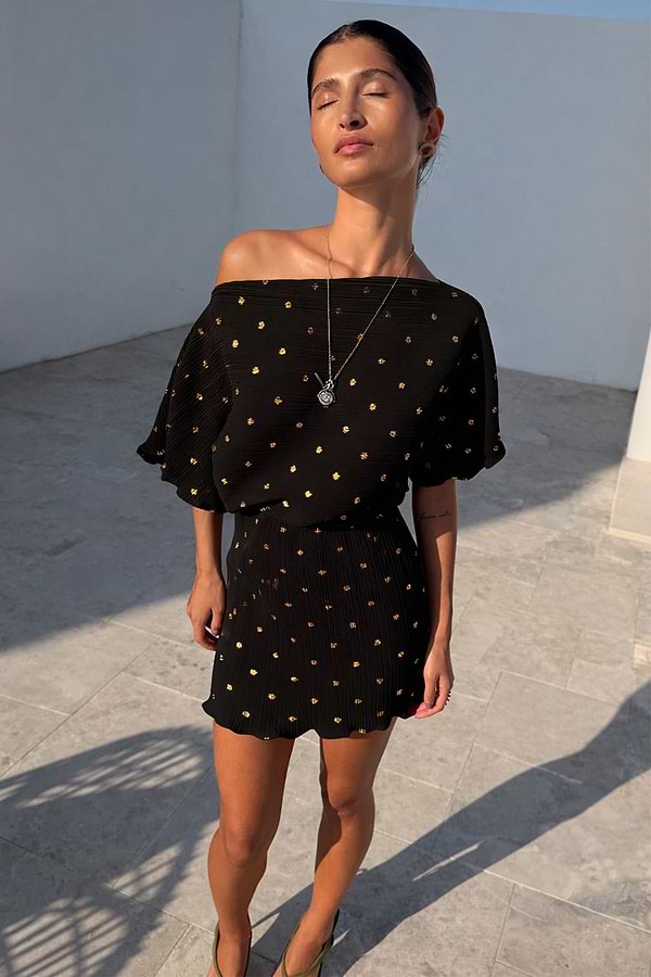 Black Plisse Mini Tilly Dress with gold metallic dots and an off-the-shoulder neckline, styled on a model.