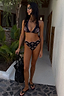 Black Palm Embroidered High Leg Brief with pink crochet trim and palm embroidery, worn by a model in a vacation setting.