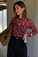 Cherry Mesh Long Sleeve Top in red sheer mesh with a cherry print, paired with black trousers and a brown bag.