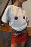 Thumbnail for White cotton Cherry Boob T-Shirt with a relaxed fit and cherry print, tucked into a leopard and red lace skirt.