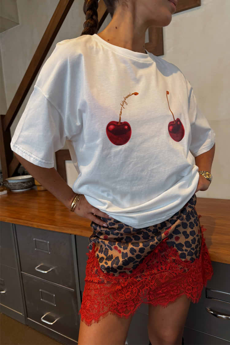 White cotton Cherry Boob T-Shirt with a relaxed fit and cherry print, tucked into a leopard and red lace skirt.