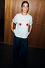 Thumbnail for White Cherry Boob T-Shirt in cotton with a boxy fit and cherry print, styled with navy pinstripe trousers.