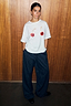 White cotton Cherry Boob T-Shirt with a cherry print and relaxed fit, paired with navy pinstripe trousers.