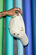 Cream Choose Love Cap with embroidered icons, held by a hand against a backdrop of colourful paper rolls.