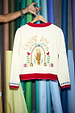 White Choose Love Cardigan with red ribbed trims and vibrant back embroidery of a hand, florals, and text.