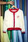 Thumbnail for White Choose Love Cardigan in a knit with red trims, heart embroidery and blue cuff details.