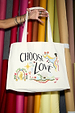 Choose Love tote bag in a recycled cotton blend featuring hand-drawn graphics against colourful fabric rolls.