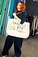 Recycled Choose Love Tote Bag in cream with colourful illustrations, carried by a woman in a pinstripe suit.