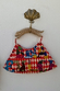 Cirque Bag with red chequered print and hand-embroidered beaded motifs, hanging by its carved wooden leopard handle.