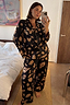 Black Deloris Button Through Pyjamas featuring gold hand, heart and eye prints, worn by a model in a mirror selfie.