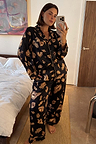 Black Deloris Button Through Pyjamas featuring gold hand, heart and eye prints, worn by a model in a mirror selfie.