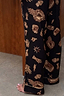 Thumbnail for Deloris Button Through Pyjama bottoms in black, showcasing the gold hand, heart and eye print with piped hems.