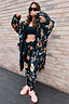 Waterproof Navy Charm Coat with a colourful sun and moon motif print and fleece lining, styled against a brick wall.