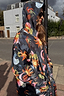 Navy Charm Coat with a colourful sun and moon print, waterproof fabric and hood, worn in an outdoor street setting.