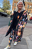 Navy Charm Coat with a colourful sun and moon print and borg lining, worn by a woman walking on a London street.
