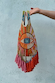 Dolce Vita Eye Bag with an iconic beaded eye motif, multicoloured glass beads and vibrant pink and orange tassels.