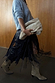 Black leather fringe belt with long tassels, styled with a blue jumper and tan boots for a layered look.