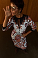 Thumbnail for Multi-wear Geometric Gaia Dress in pleated plisse fabric with abstract motifs and a tie-neck detail.