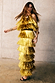Gold Fringe Dress featuring tiered gold foil tassels and a midaxi length, styled with gold jewelry and black heels.