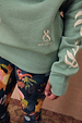 Sage Sundazed Accessible Sweatshirt with cream palm print, embroidered logo, and thumb hole detail.