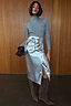 Grey Gunmetal Rib Knit Jumper with a roll neck and shimmering silver flecks, tucked into a silver metallic skirt.