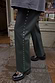 Bottle green vegan leather trousers with silver side studs, styled with chunky loafers in a street style setting.