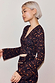 Dark Leopard Ballet Wrap top with flared sleeves and a wrap tie closure in an iconic leopard print with orange accents.
