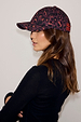 Dark Leopard Cap featuring an iconic burgundy animal print, worn with a black top for a casual look.