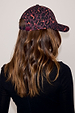 Dark Leopard Cap in iconic burgundy leopard print with adjustable back strap, shown on a model.