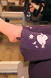 Orange cotton crew sock with leopard print detail worn with embroidered purple trousers in a gym.