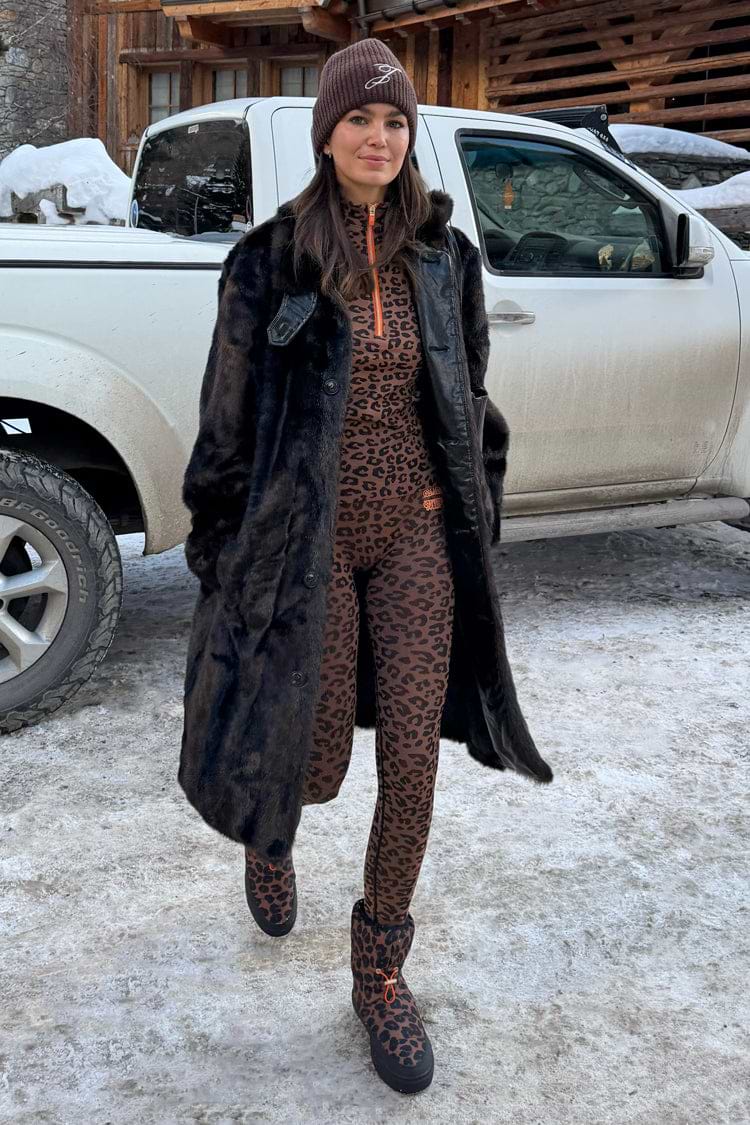 Leopard print thermal leggings and matching top styled with a dark coat in a snowy setting.