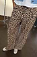 Thumbnail for Lucia Leopard Elissa Trousers featuring a wide-leg fit and iconic leopard print, paired with silver trainers.