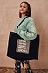 Black canvas Life Is Tough Tote Bag featuring an iconic leopard print slogan graphic, styled over the shoulder.