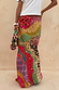 Morocco Beaded Bag with hand-beaded abstract motifs, held by a model wearing a matching vibrant printed maxi skirt.