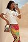 Morocco Beaded Bag featuring hand-beaded abstract patterns in autumnal tones, styled by a model in a summer setting.