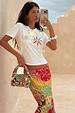Morocco Beaded Bag featuring hand-beaded abstract patterns in autumnal tones, styled by a model in a summer setting.