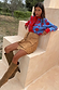 Blue and red Holly Cardigan with sun motifs, styled with a tan suede mini Jaspre skirt and brown boots.