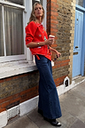 Red Mystical Cardigan with jacquard motifs and blanket stitch detail, styled with wide-leg jeans for a London street look.