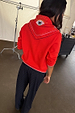 Red Mystical Knit Bandana with an embroidered eye motif and gold details, styled over a red jumper from behind.