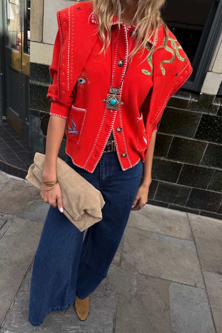 Red Mystical Knit Bandana with iconic eye and snake motifs, draped over shoulders in a street style look.