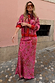 Pink Paisley Dorris Skirt and matching knit cardigan with red trim, worn by a model on a cobblestone street.